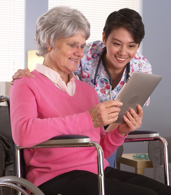 nurse aiding elderly woman with her tablet